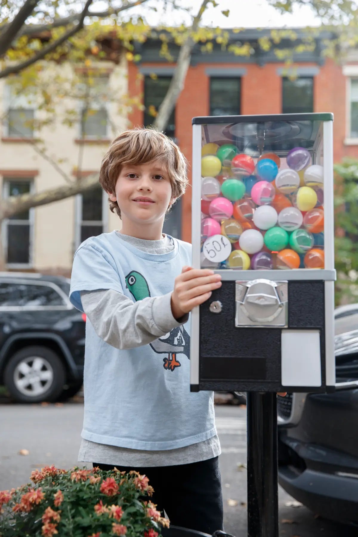 Linus, 8, next to his gumball vending machine, outside, that sells his illustrated pinback buttons.